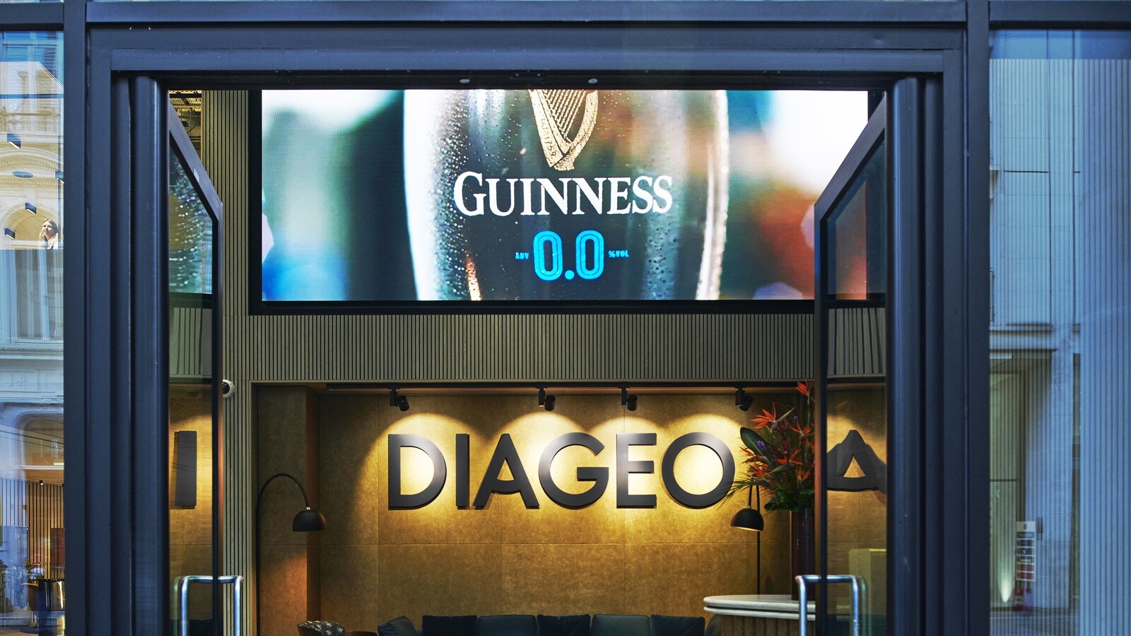 ロンドンにあるディアジオのグローバル本社エントランス。壁面の「DIAGEO」サインと、その上でギネスを映すデジタルサイネージ。