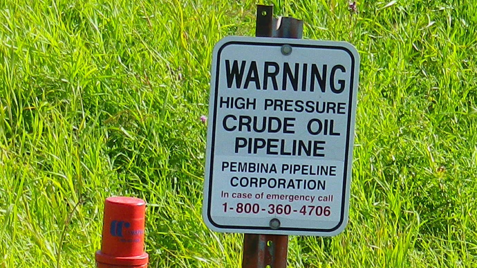 アルバータ州の原油パイプライン用地に立つ Pembina Pipeline Corporation の警告標識。手前は同社パイプラインの位置を示すマーカー杭。